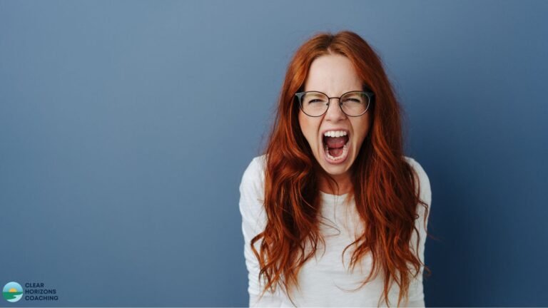 Red-haired woman with glasses is staring straight out of the picture. Her mouth is wide open and she is angry / screaming